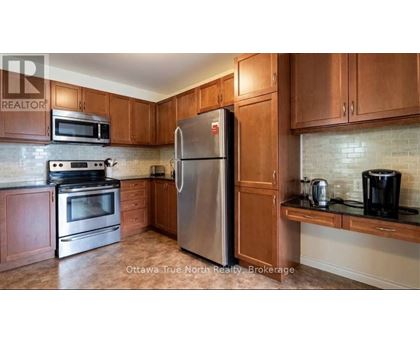 A kitchen with a stainless steel refrigerator, microwave, oven, and coffee maker.