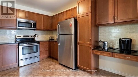 A kitchen with a stainless steel refrigerator, microwave, oven, and coffee maker.