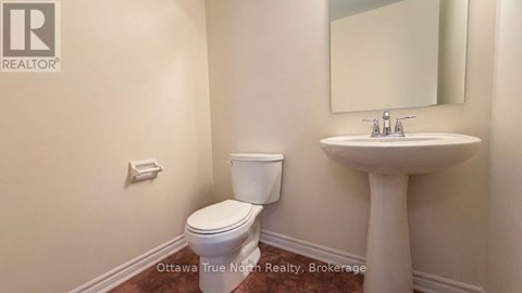 A bathroom with a toilet, sink, and mirror.