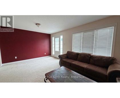 A living room with a brown couch and a window with blinds.