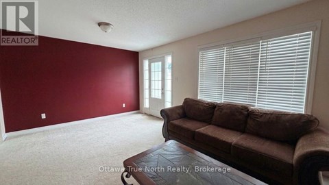 A living room with a brown couch and a window with blinds.