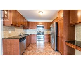 A kitchen with wooden cabinets and a black refrigerator.