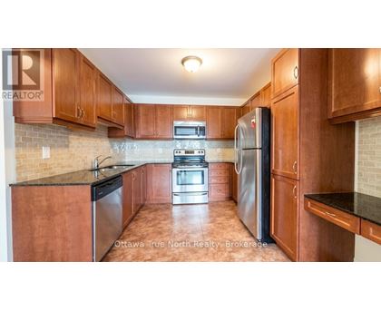 A kitchen with wooden cabinets and a black refrigerator.