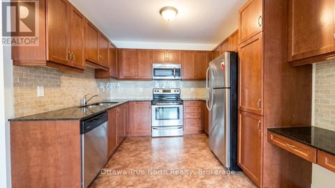 A kitchen with wooden cabinets and a black refrigerator.