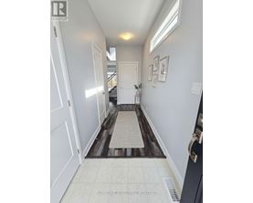 A hallway with a rug on the floor and pictures on the wall.
