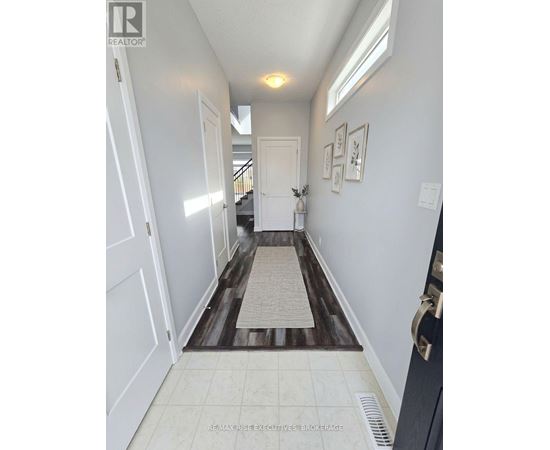 A hallway with a rug on the floor and pictures on the wall.