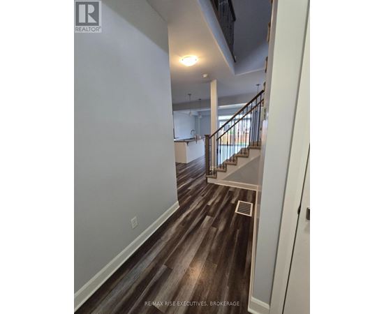 A hallway with wood flooring and a staircase.