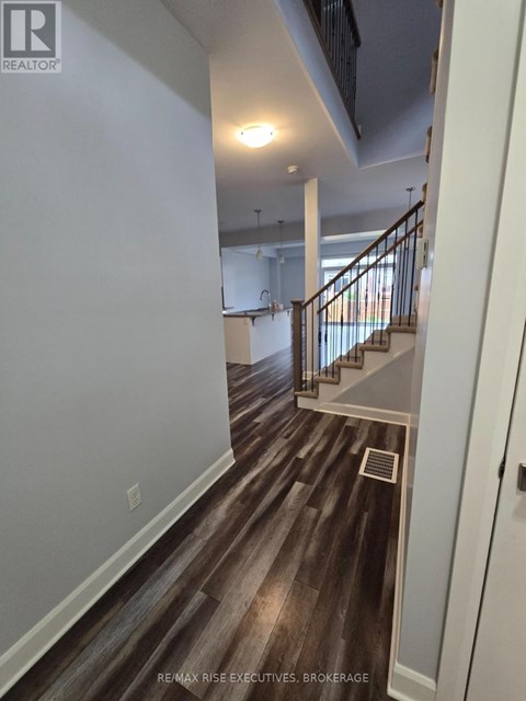 A hallway with wood flooring and a staircase.