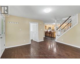 A spacious room with wooden floors and a staircase leading to another room.