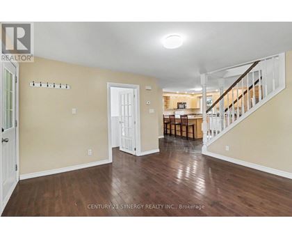 A spacious room with wooden floors and a staircase leading to another room.
