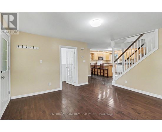 A spacious room with wooden floors and a staircase leading to another room.
