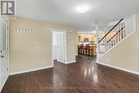 A spacious room with wooden floors and a staircase leading to another room.