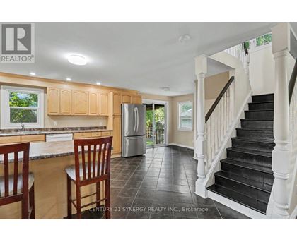 A kitchen with wooden cabinets and a black staircase.