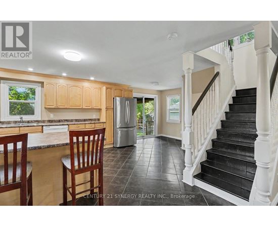 A kitchen with wooden cabinets and a black staircase.