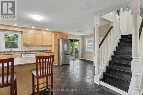 A kitchen with wooden cabinets and a black staircase.