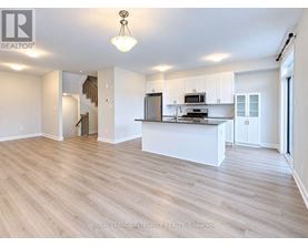 A spacious kitchen with white cabinets and a wooden floor.