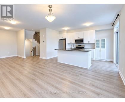 A spacious kitchen with white cabinets and a wooden floor.