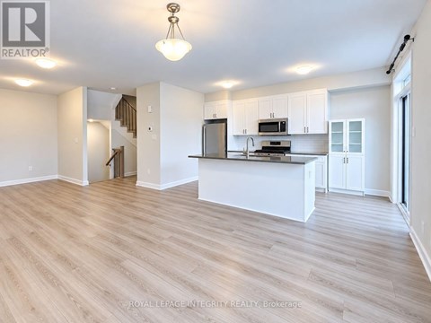 A spacious kitchen with white cabinets and a wooden floor.
