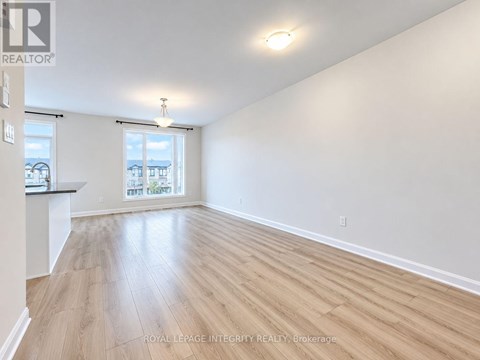 A spacious room with wooden flooring and a window overlooking a balcony.