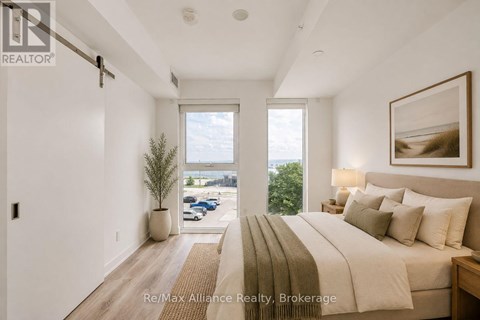 A bedroom with a large bed and a view of the outdoors through a window.