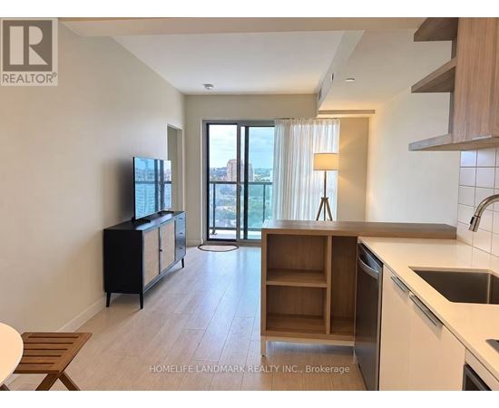 A kitchen with a sink, stove, and cabinets with a sliding glass door leading to a balcony.