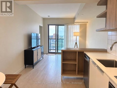 A kitchen with a sink, stove, and cabinets with a sliding glass door leading to a balcony.