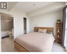 A bedroom with a large bed and a wooden bookshelf.