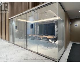 A glass wall separates a conference room from a hallway.