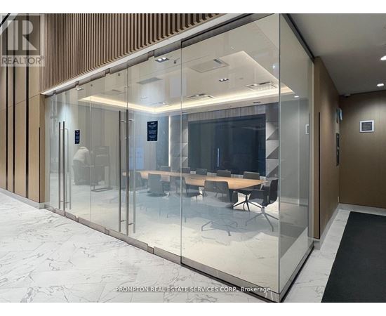 A glass wall separates a conference room from a hallway.