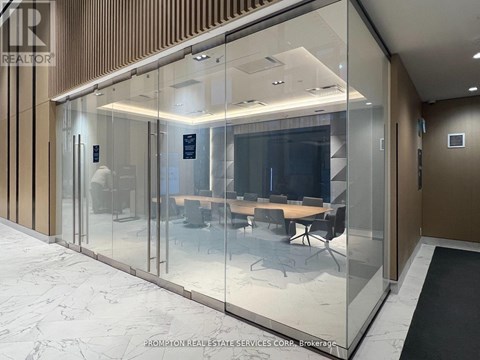 A glass wall separates a conference room from a hallway.