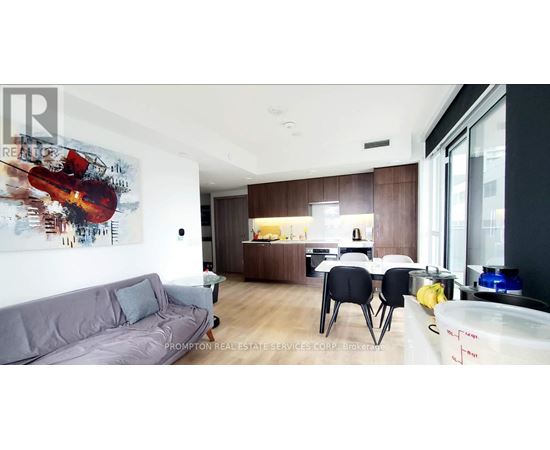 A modern living room with a grey couch and a painting of a violin on the wall.