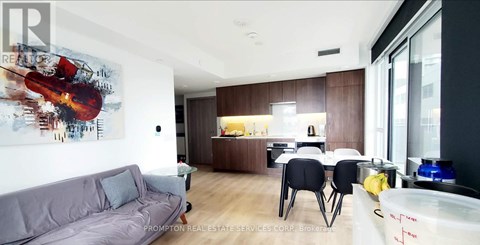 A modern living room with a grey couch and a painting of a violin on the wall.