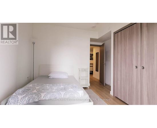 A bedroom with a bed, a nightstand, and a wardrobe.