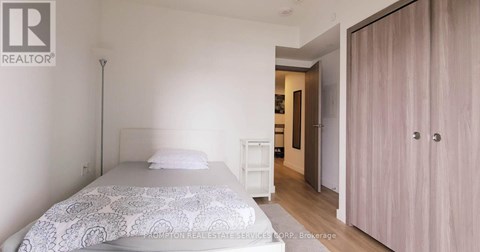 A bedroom with a bed, a nightstand, and a wardrobe.