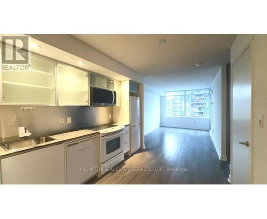 A kitchen with stainless steel appliances and wooden floors.