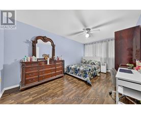 A bedroom with a large dresser and a bed with a blue and white comforter.