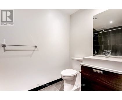 A bathroom with a toilet, sink, and mirror.