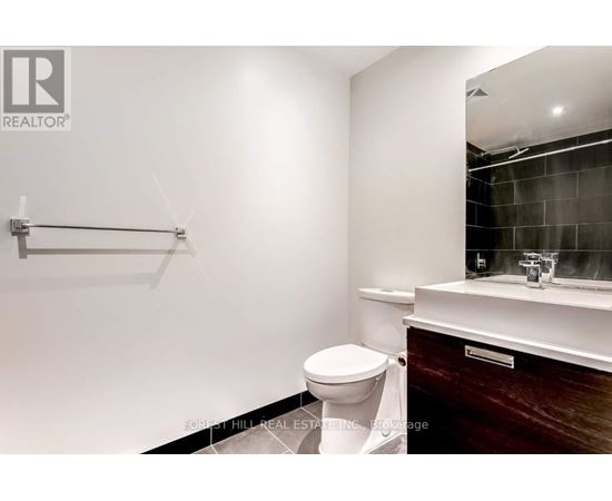 A bathroom with a toilet, sink, and mirror.