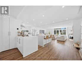 A modern kitchen with white cabinets and a wooden floor.