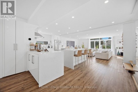 A modern kitchen with white cabinets and a wooden floor.