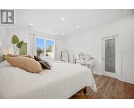A bedroom with a large bed and a window overlooking a garden.