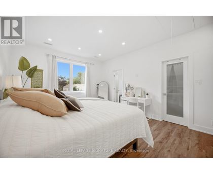 A bedroom with a large bed and a window overlooking a garden.