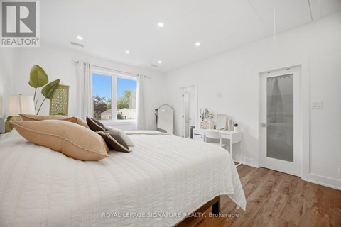 A bedroom with a large bed and a window overlooking a garden.