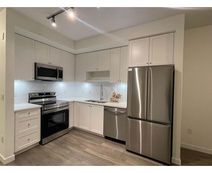 A kitchen with a stainless steel refrigerator, oven, and microwave.