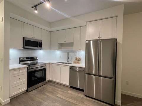 A kitchen with a stainless steel refrigerator, oven, and microwave.