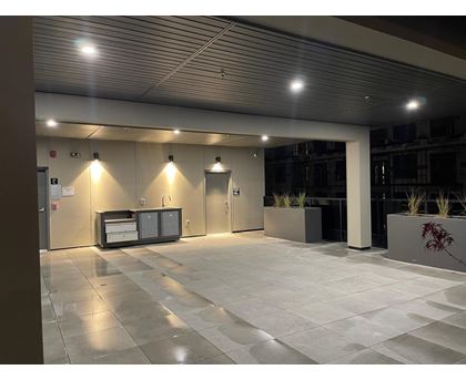 A modern building lobby with a reception desk and potted plants.