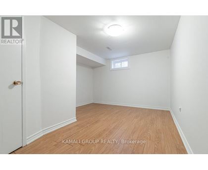 A room with wooden flooring and a window in the corner.