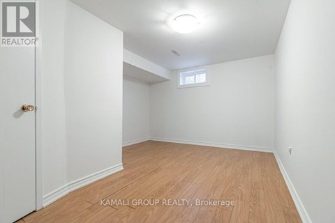 A room with wooden flooring and a window in the corner.