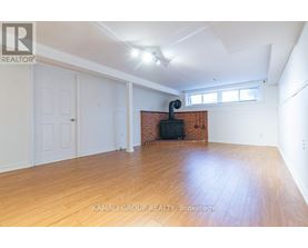 A room with wooden flooring and a brick fireplace is on the market with Kamali Group Realty.