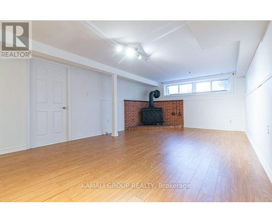 A room with wooden flooring and a brick fireplace is on the market with Kamali Group Realty.